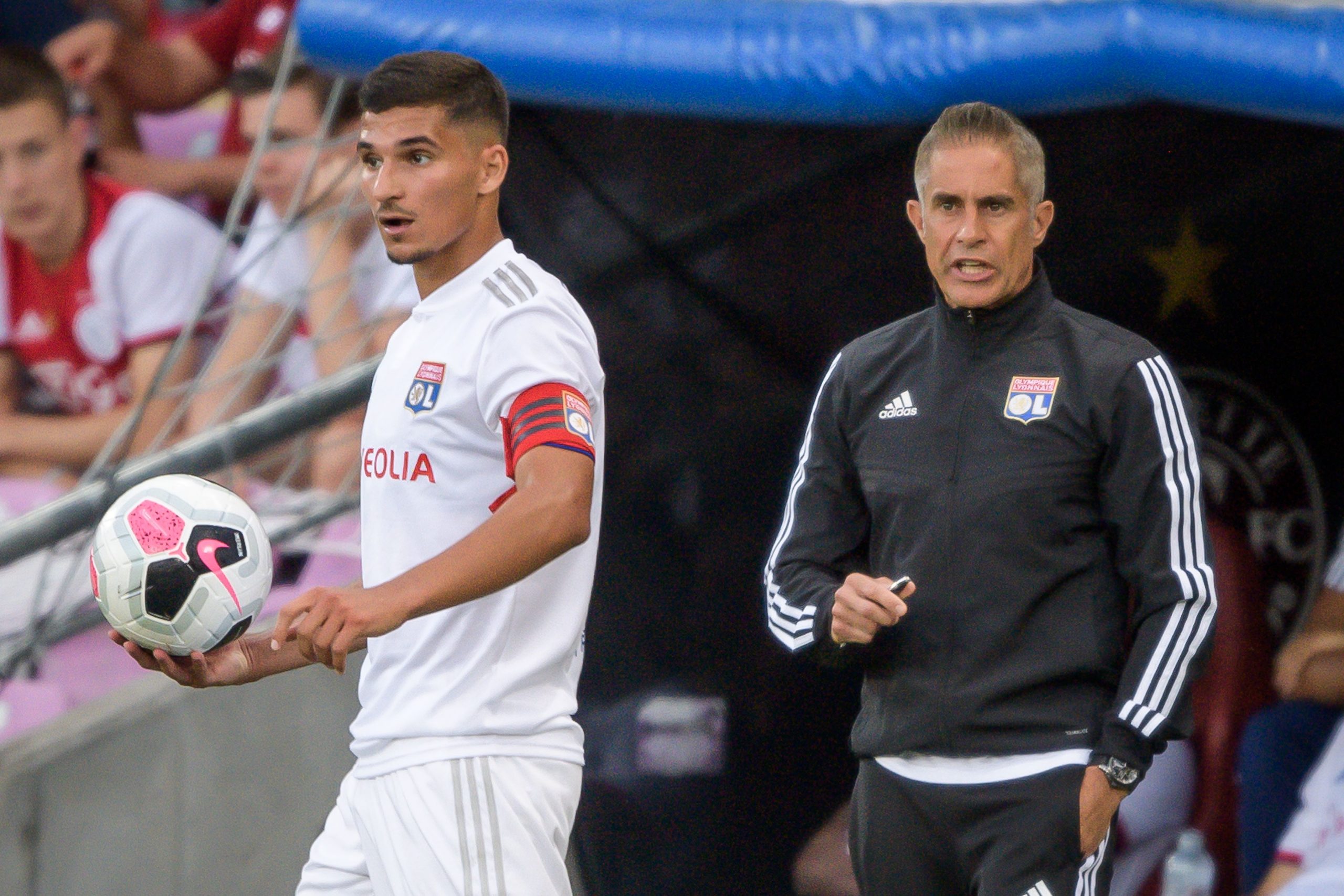 Sylvinho (R) looks on behind Lyon's French midfielder, Houssem Aouar.