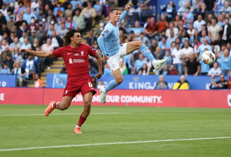 Phil Foden of Manchester City kicks the ball under pressure from Trent Alexander-Arnold of Liverpool. (