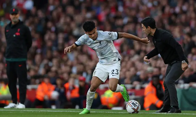 Jurgen Klopp of Liverpool and Mikel Arteta of Arsenal watch Luis Diaz control the ball in a league game.